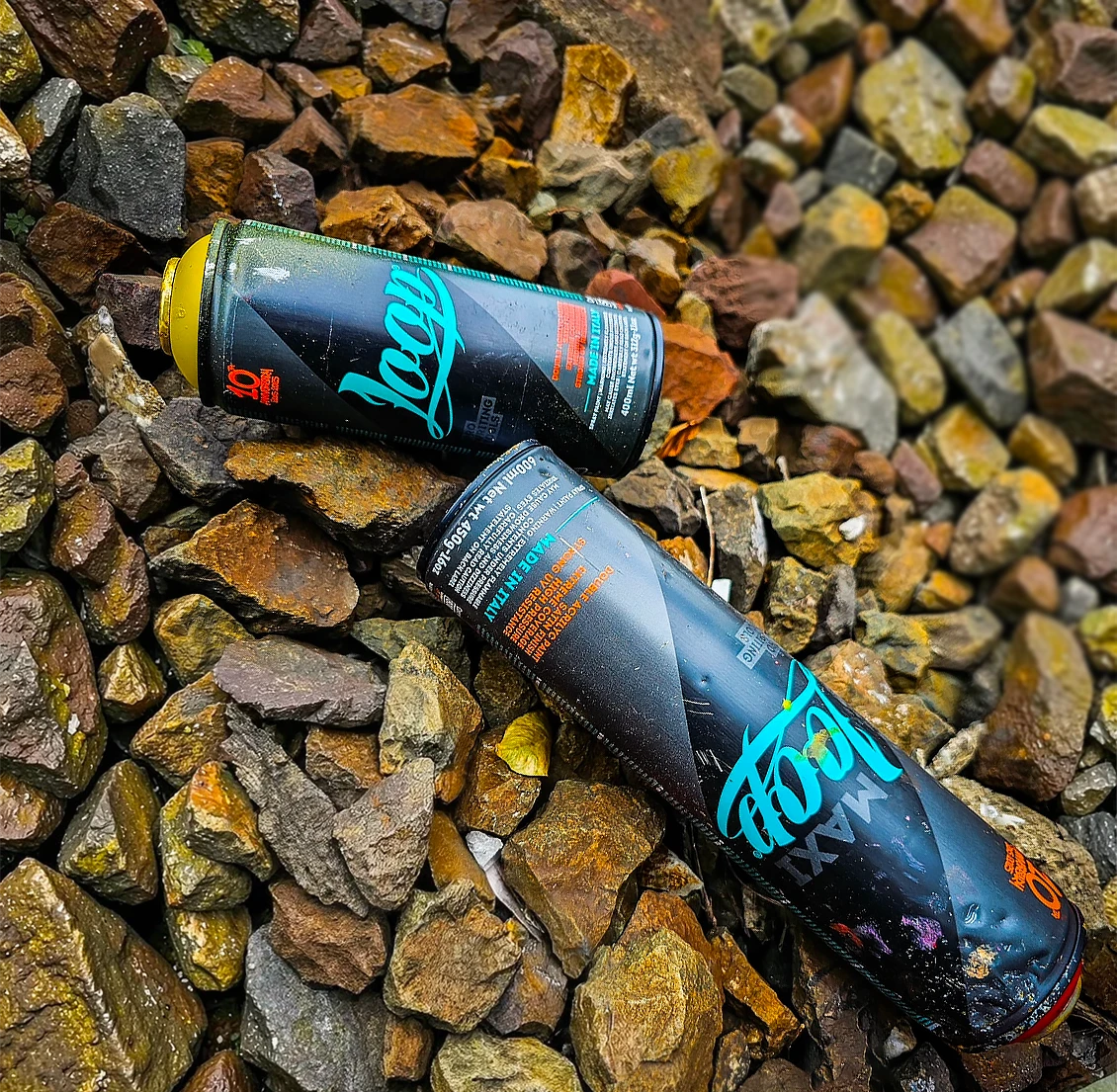 Two spray paint cans on a bed of stones