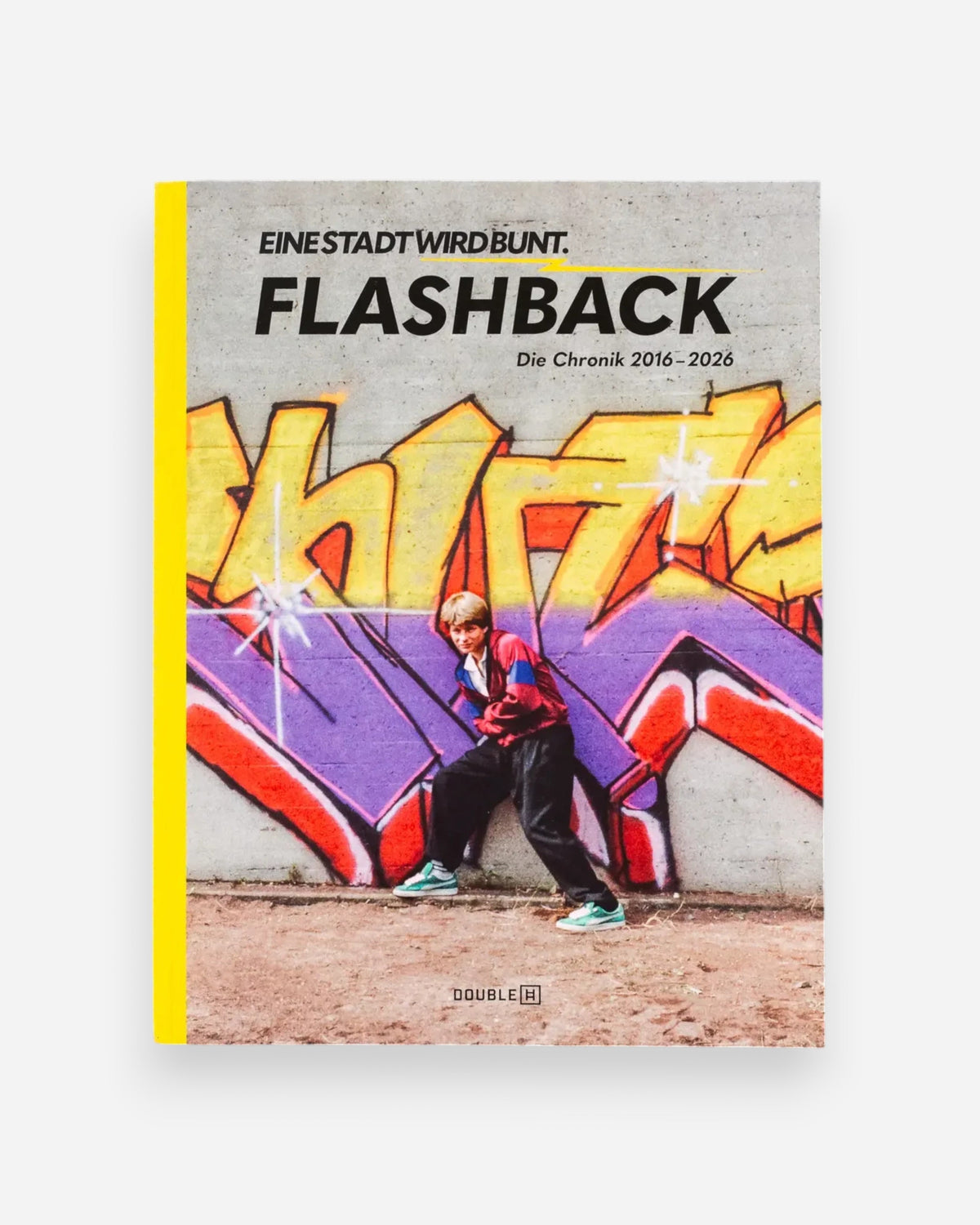 Astrofat EINE STADT WIRD BUNT. FLASHBACK book cover featuring graffiti art and a person posing in front of a wall.