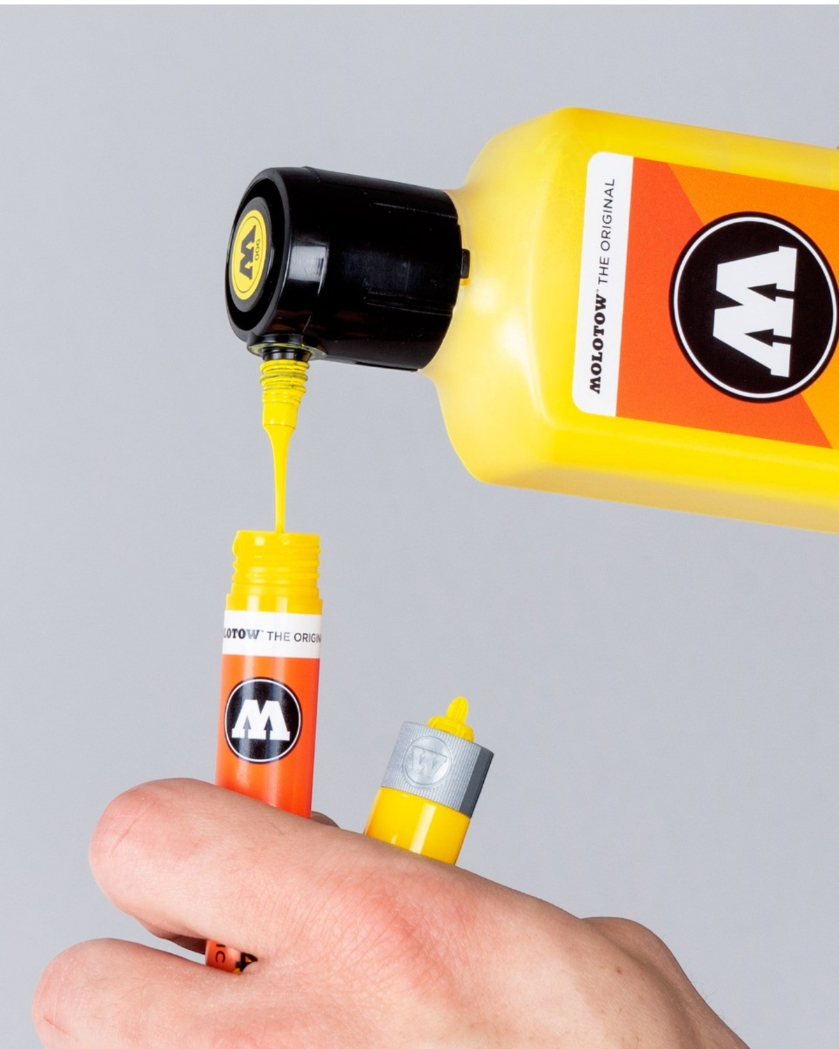 Astrofat Molotow One4All acrylic paint marker being refilled with yellow ink from a bottle