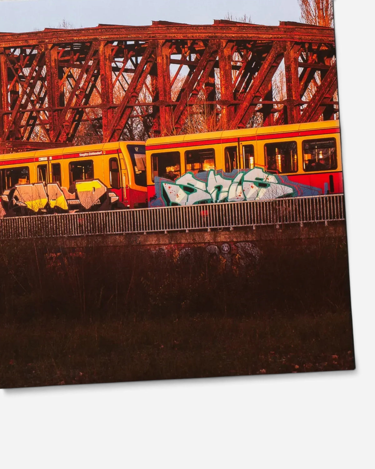 Astrofat photography book page showing a yellow Berlin S-Bahn train with graffiti crossing a rusty metal bridge.